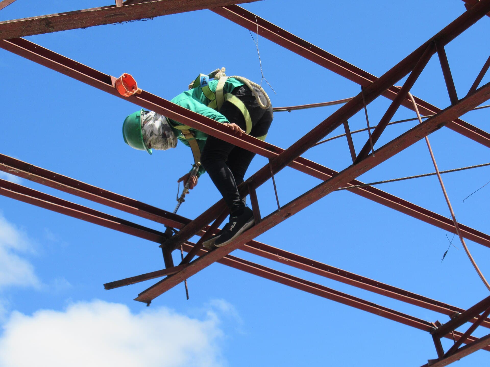 A welder in a green hard hat working on a metal structure