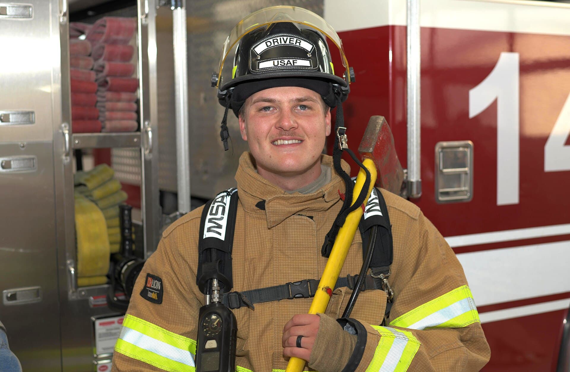 A U.S. Air Force firefighter standing beside a fire truck